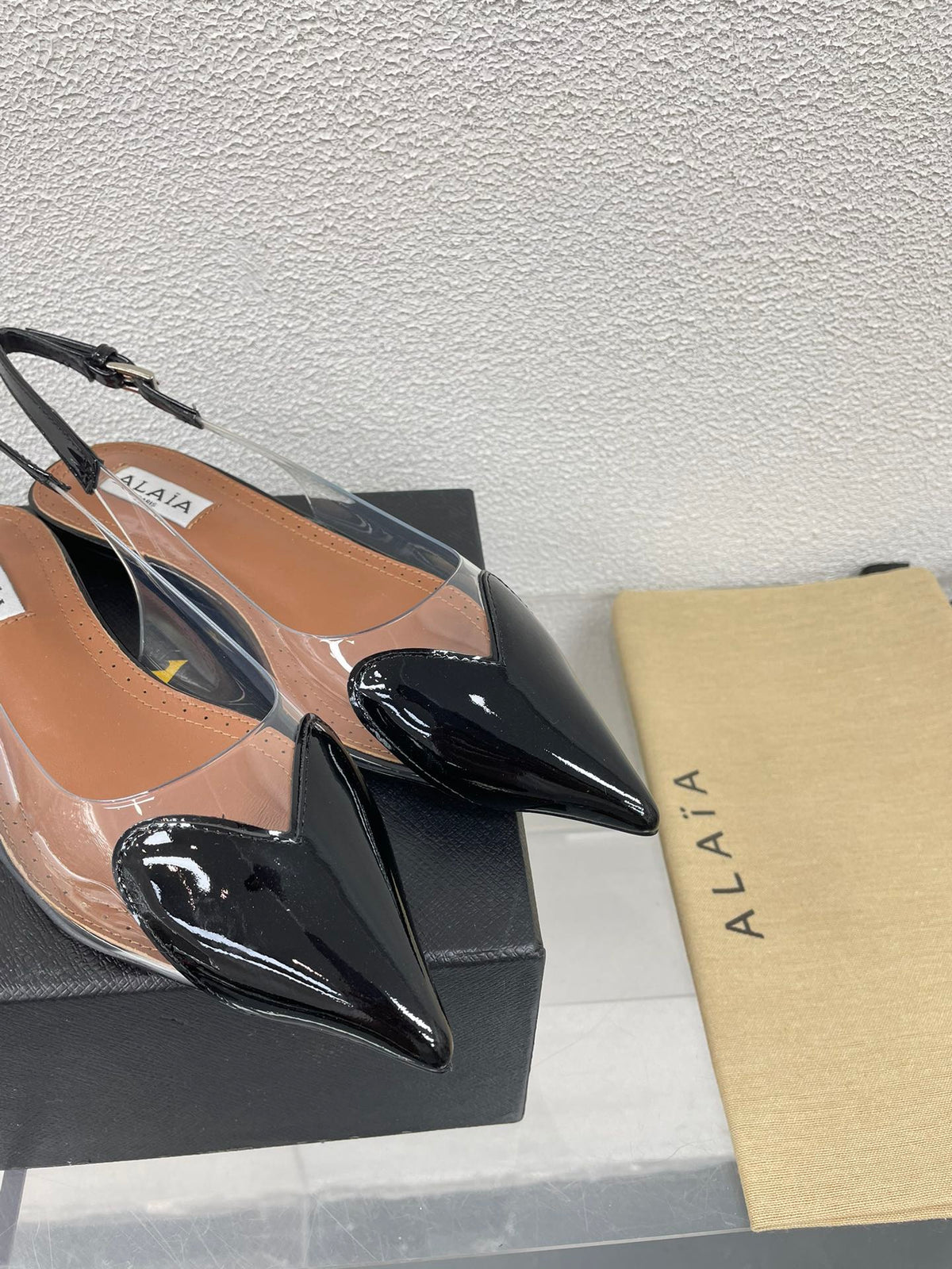 ALAIA LE COEUR FLAT SLINGBACKS IN BLACK PATENT LAMBSKIN